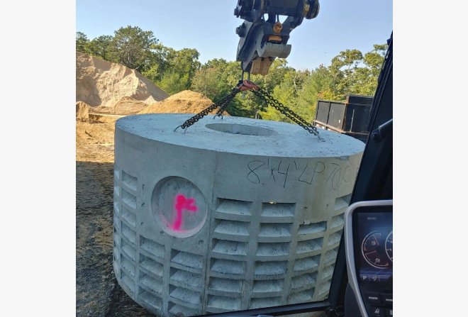 A large concrete tank being lifted by crane.