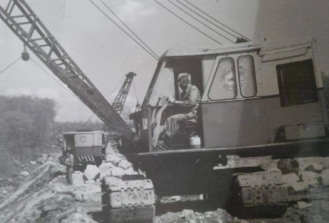 A man sitting on the back of an old tractor.