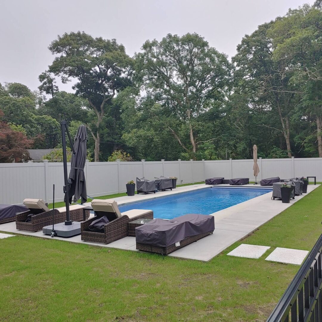 A pool with a black umbrella and some chairs